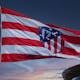 Waving Atlético Madrid flag against a sunset sky, symbolizing team spirit in Madrid.